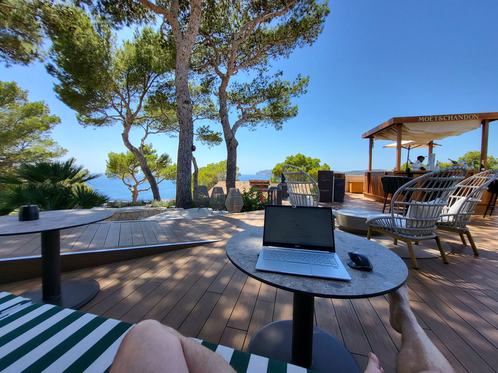 Laptop auf einem Tisch auf einer Terrasse unter Pinien